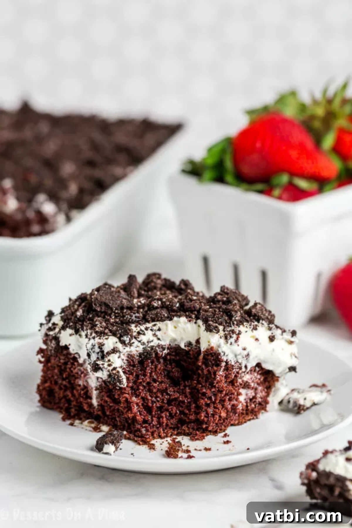 Chocolate and Oreo lovers will go crazy over this Oreo poke cake recipe. This cake is so rich and delicious for the perfect dessert. Plus, it is so easy! Close up image of a slice of irresistible Oreo poke cake on a pristine white plate, showcasing layers of chocolate cake, creamy pudding, and crushed Oreo topping.