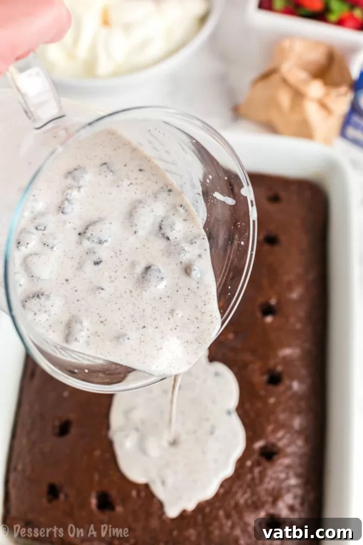 Ultimate Oreo Poke Cake 2 Oreo pudding filling being gently poured over the warm chocolate poke cake, aiming to fill the freshly poked holes for maximum absorption.