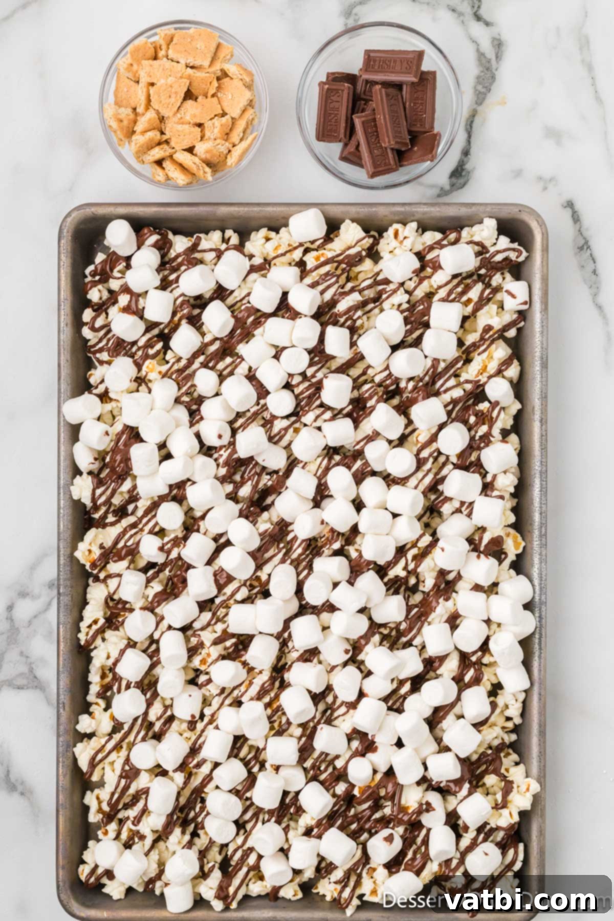 Miniature marshmallows sprinkled over the chocolate-drizzled popcorn.