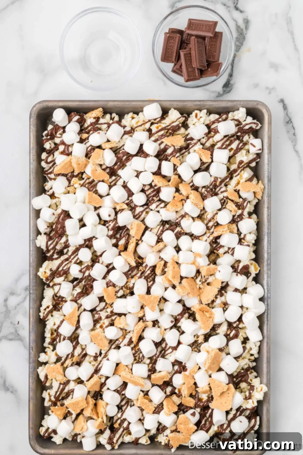 Broken graham cracker pieces scattered over the popcorn and marshmallow mixture.