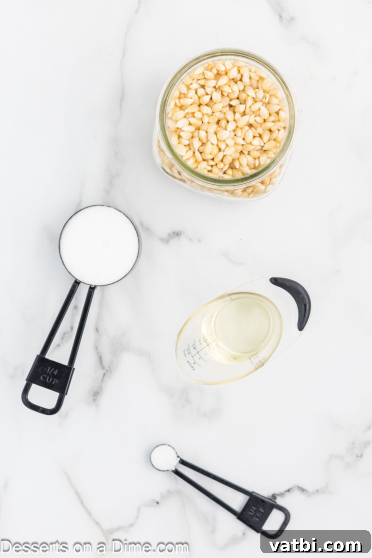 Kettle Popped Perfection 3 Four simple ingredients for kettle corn: vegetable oil, popcorn kernels, granulated sugar, and salt, laid out on a white surface.