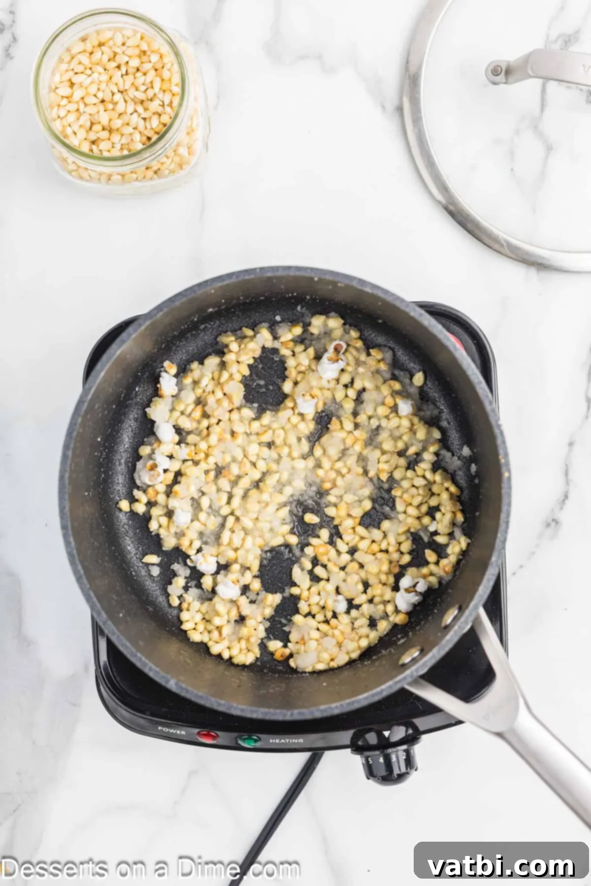Kettle Popped Perfection 5 Popcorn kernels, sugar, and salt being added to hot oil in a saucepan.