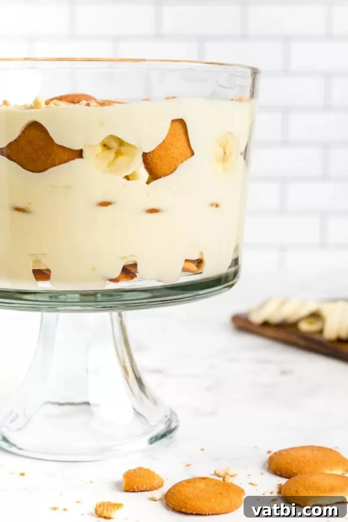 This easy and delicious homemade banana pudding recipe will be the new family favorite. All of the delicious layers make this dessert so luscious. Close-up image of luscious banana pudding layered in a clear trifle dish, topped with vanilla wafers.