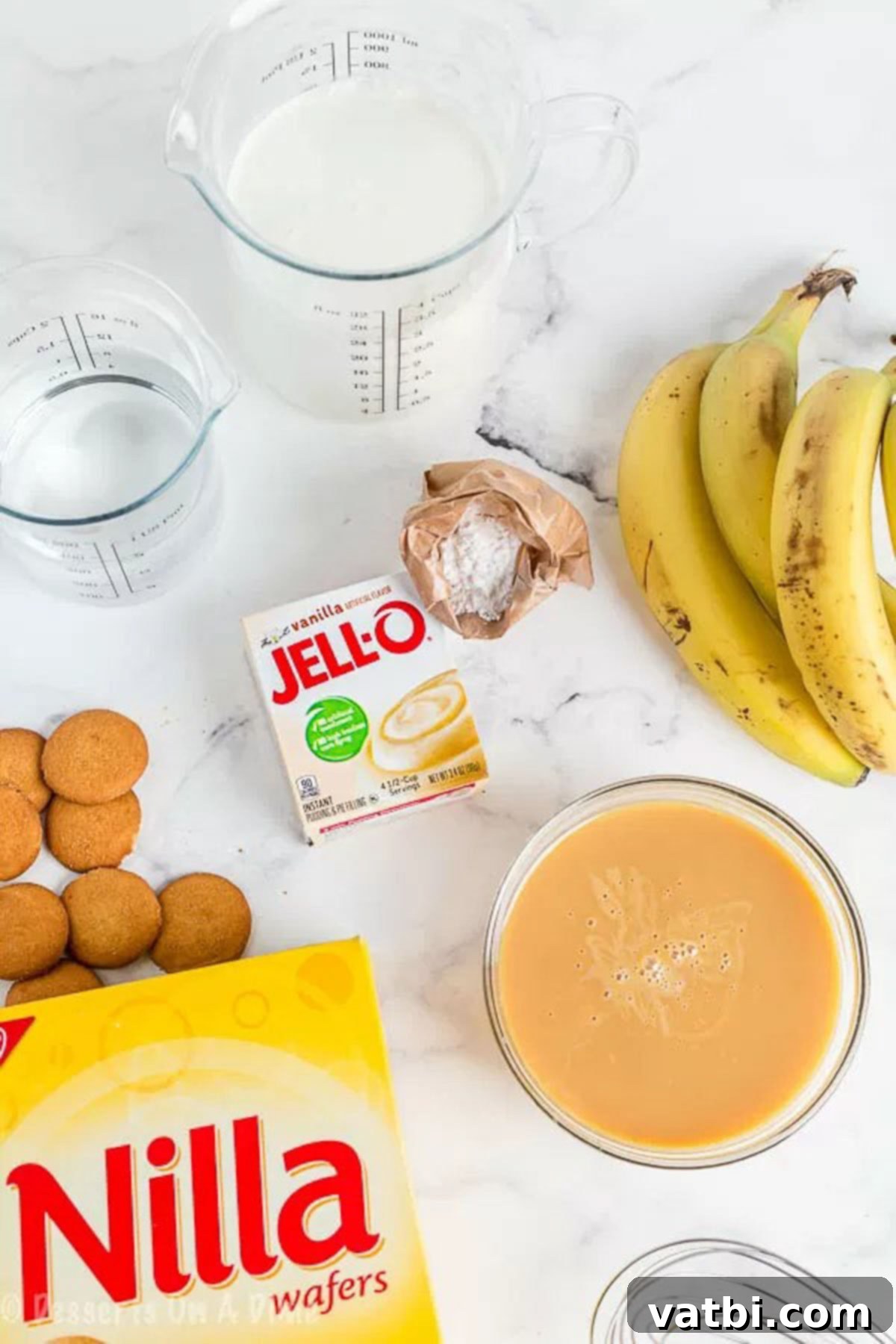 This easy and delicious homemade banana pudding recipe will be the new family favorite. All of the delicious layers make this dessert so luscious. Various ingredients for banana pudding laid out: sweetened condensed milk, vanilla instant pudding mix, heavy cream, fresh bananas, and Nilla wafers.