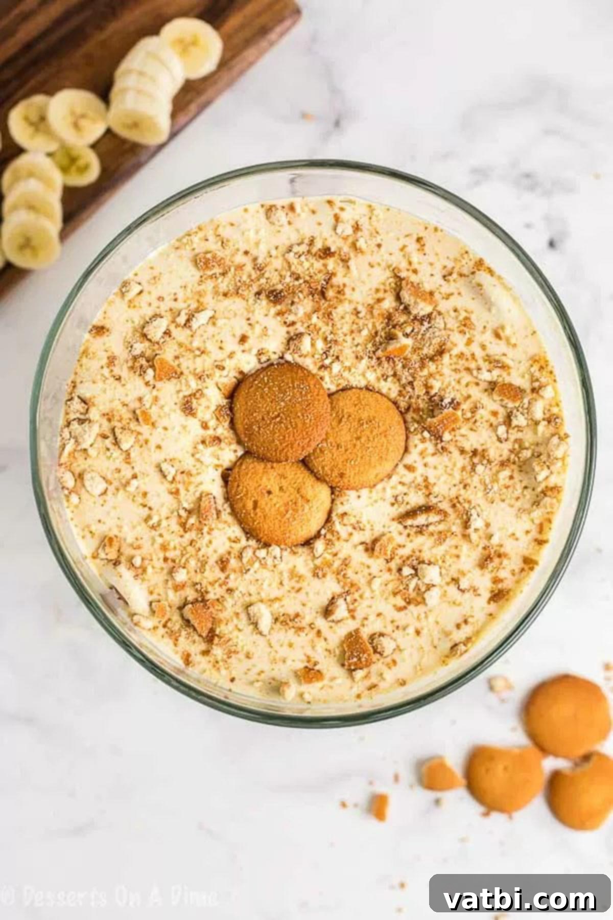 This easy and delicious homemade banana pudding recipe will be the new family favorite. All of the delicious layers make this dessert so luscious. Close-up image of assembled banana pudding in a clear serving dish, beautifully topped with additional Nilla wafers for garnish.