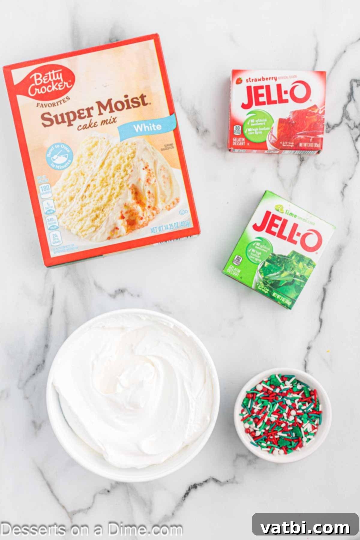 Festive Christmas Jello Poke Cake 3 Ingredients for Christmas Jello Poke Cake including white cake mix, red and green Jello packets, a tub of Cool Whip, and a bottle of festive Christmas sprinkles.