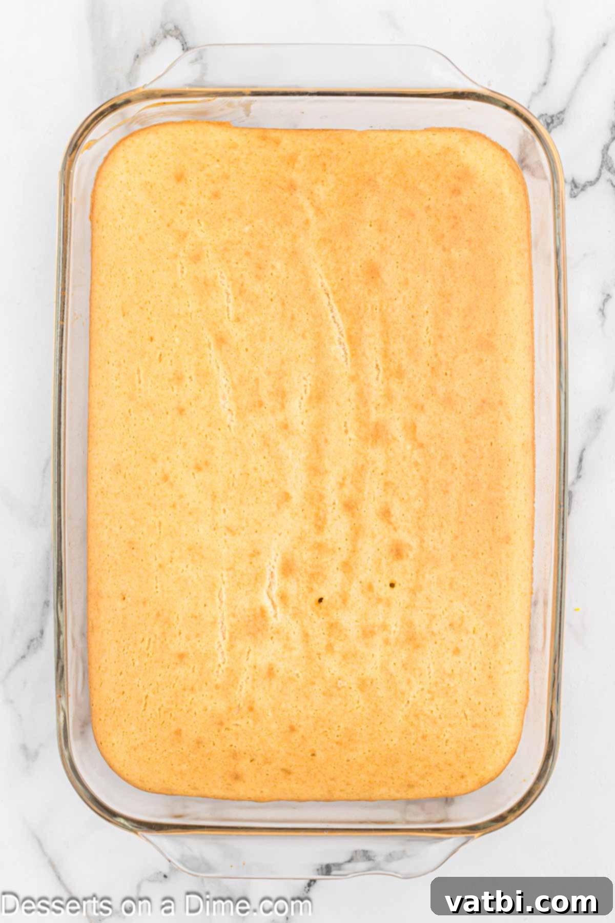 Festive Christmas Jello Poke Cake 4 A freshly baked white cake in a 9x13 inch baking dish, ready for the next step.