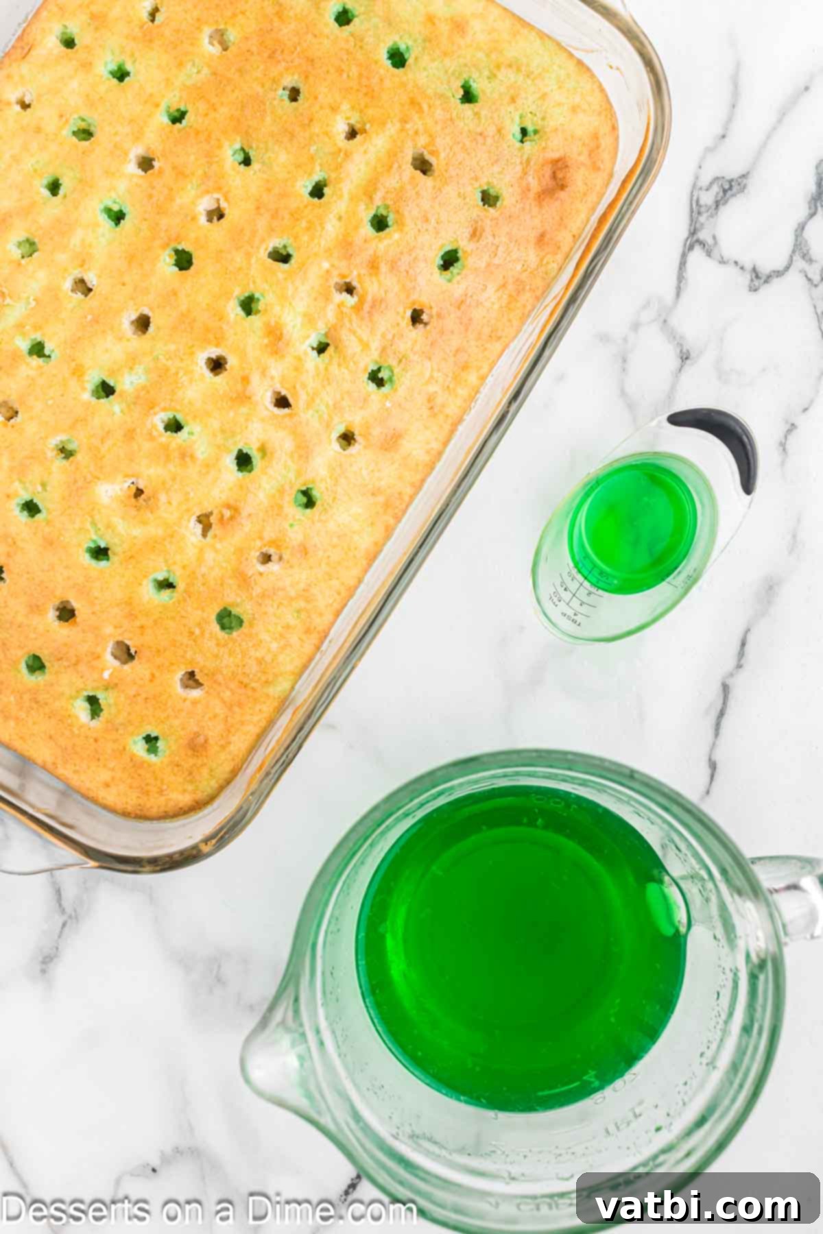 Festive Christmas Jello Poke Cake 6 Red and green Jello liquid being spooned alternately over the poked cake, starting to fill the holes.