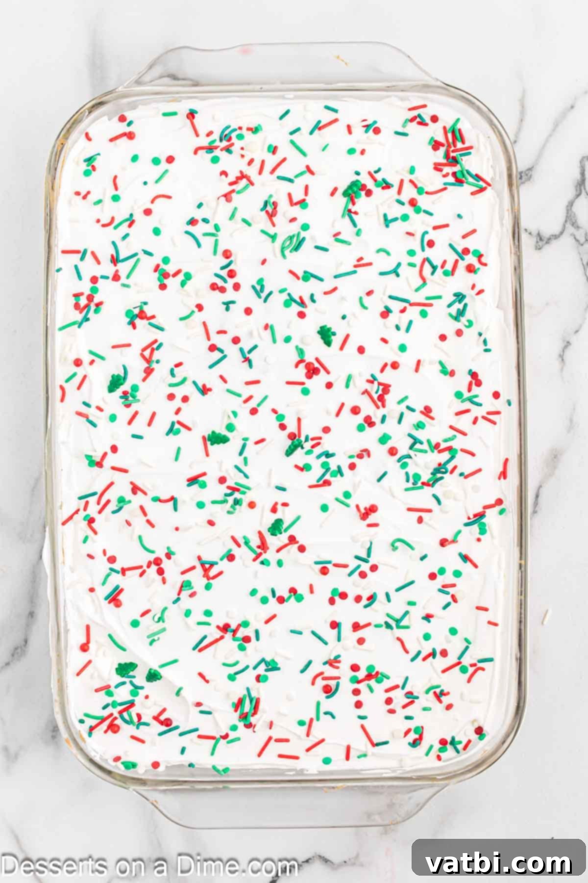 Festive Christmas Jello Poke Cake 9 The finished Christmas Jello Poke Cake topped generously with a mix of red, green, and white Christmas sprinkles.
