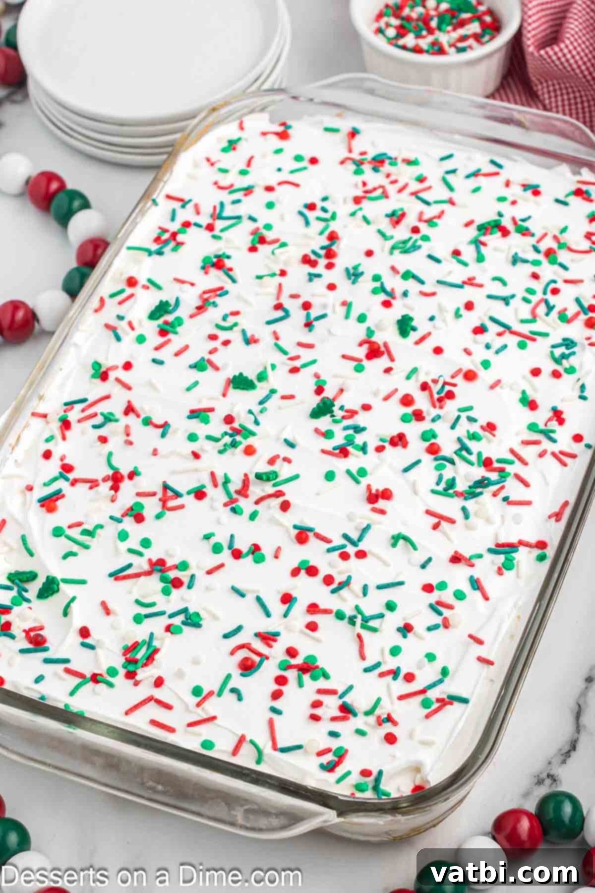 Festive Christmas Jello Poke Cake 10 A festive Christmas Jello Poke Cake, beautifully topped with a generous amount of red, green, and white sprinkles, ready to be served.