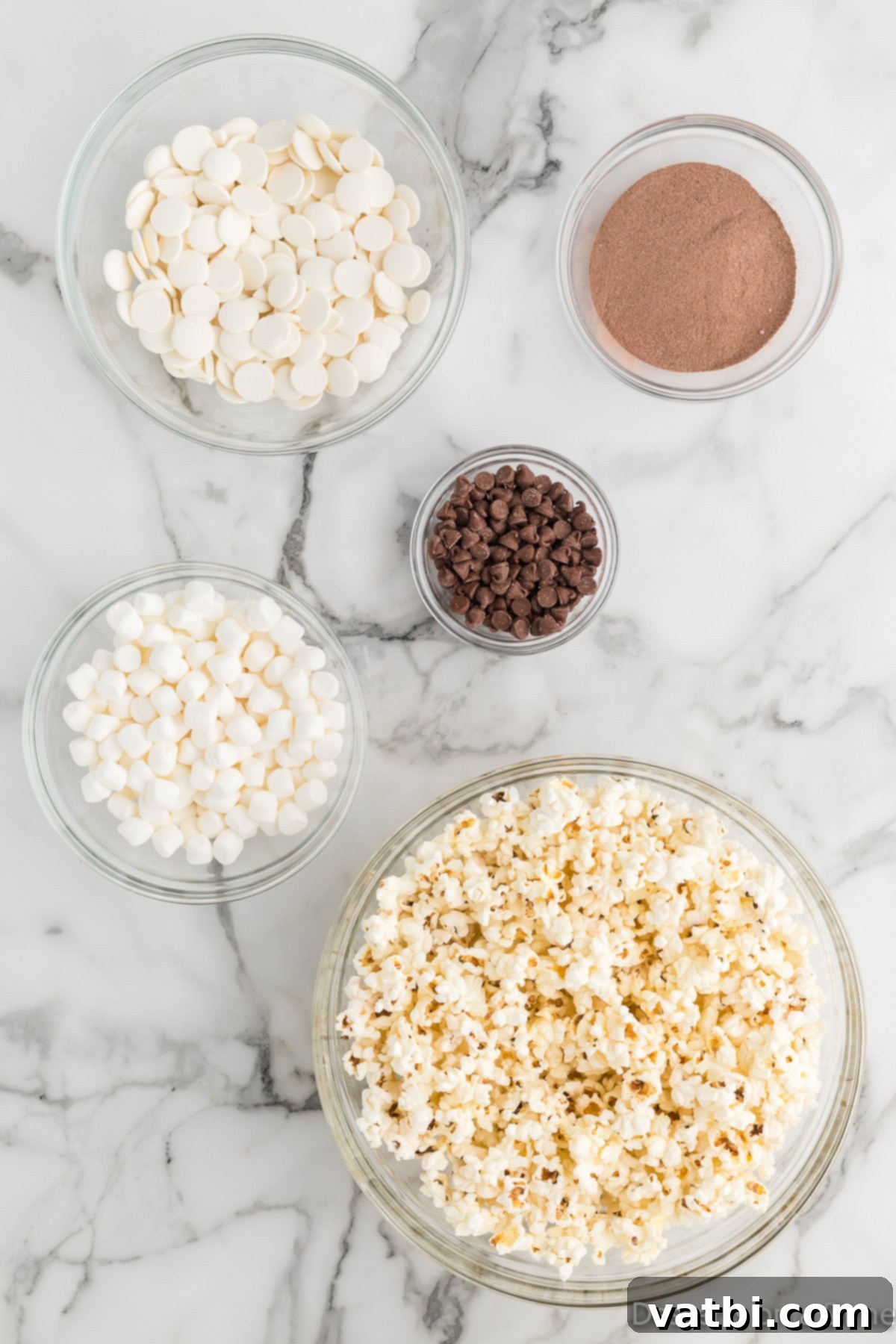 Velvet Chocolate Popcorn 3 Ingredients for Hot chocolate popcorn - popcorn, white chocolate candy melts, hot cocoa mix, mini marshmallows, chocolate chips.