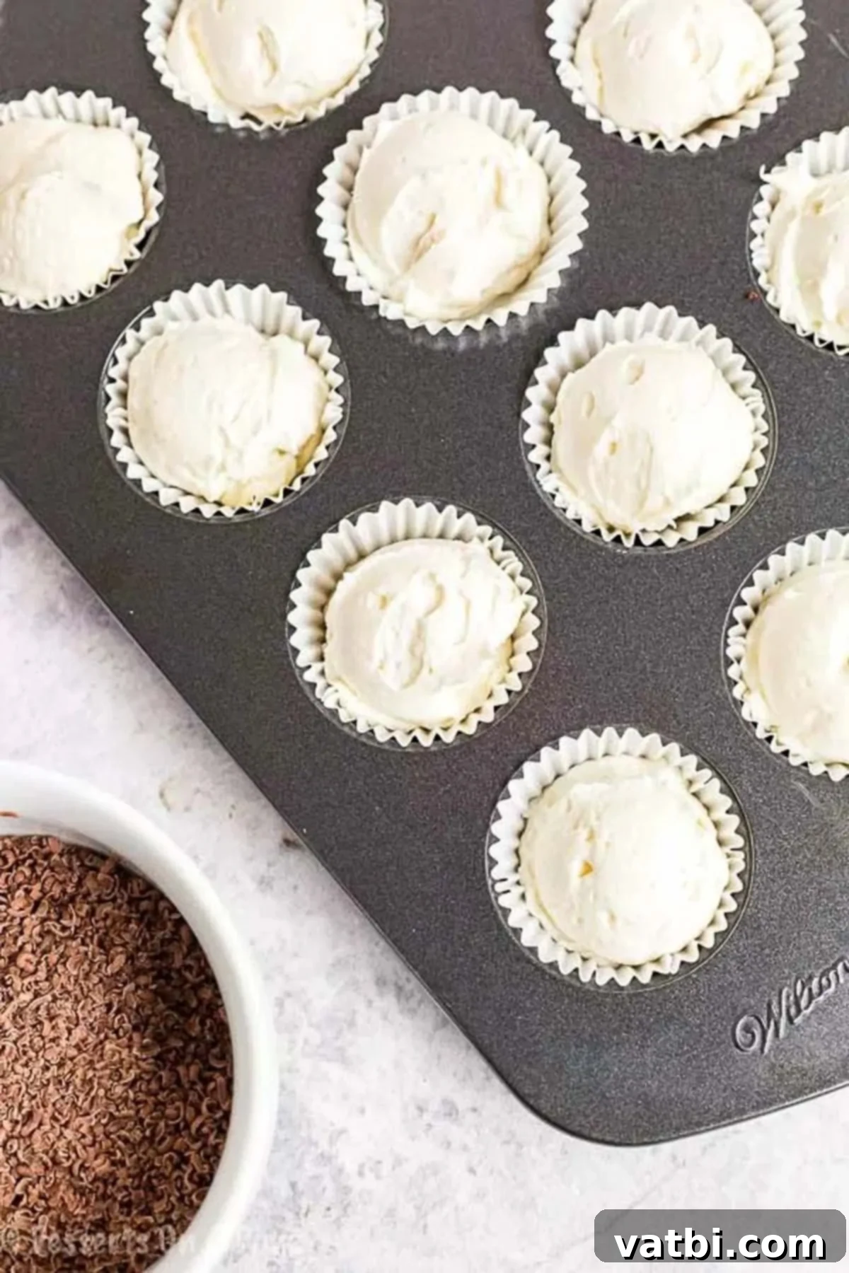Decadent Keto Cheesecake Fat Bombs 4 Mini Keto Cheesecake Fat Bombs in a muffin pan with cupcake liners, ready for sugar-free chocolate shavings.