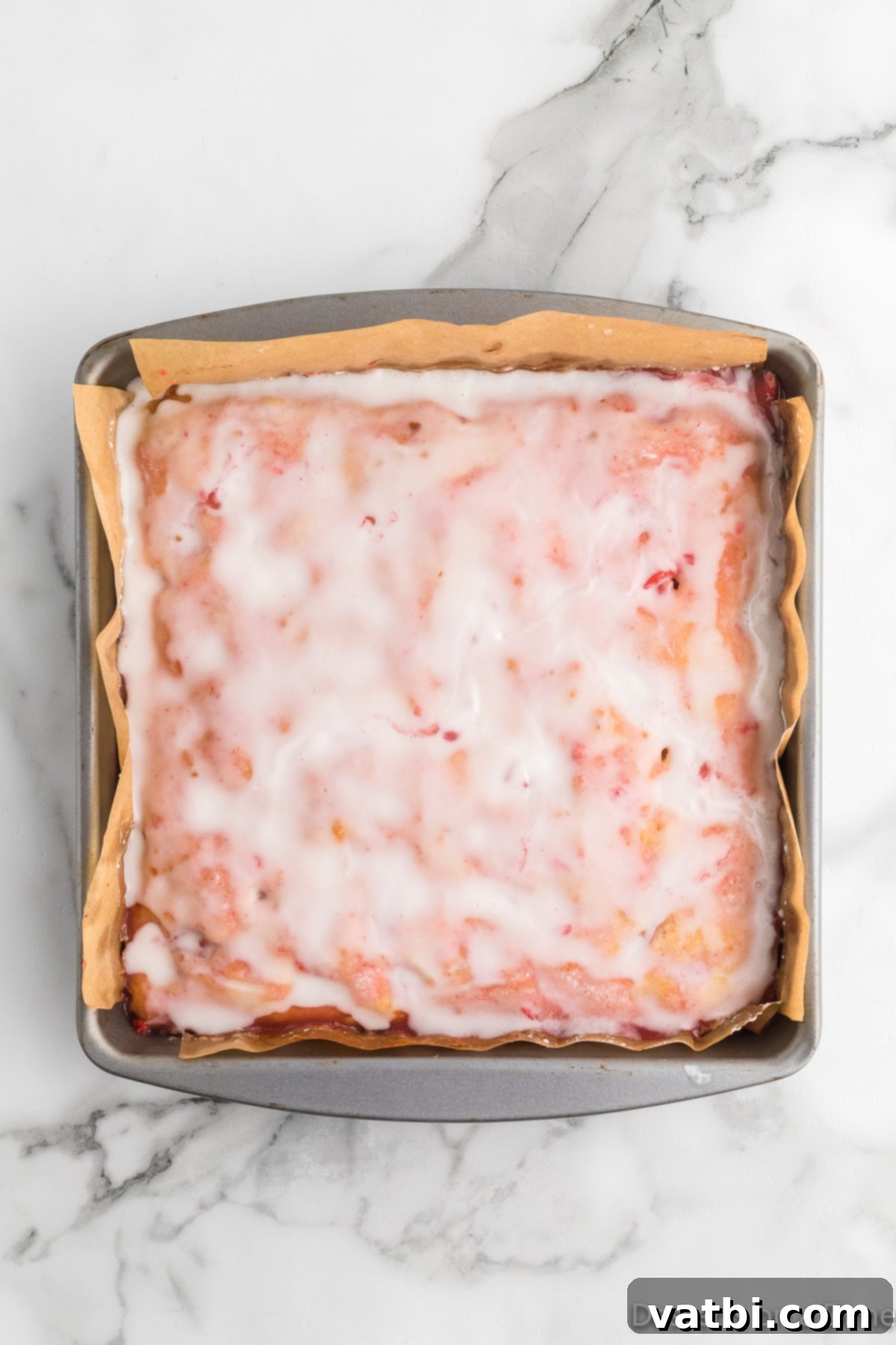 Zesty Strawberry Lemon Blondie Delight 12 Smooth pink strawberry glaze being poured and spread over the cooled blondies.