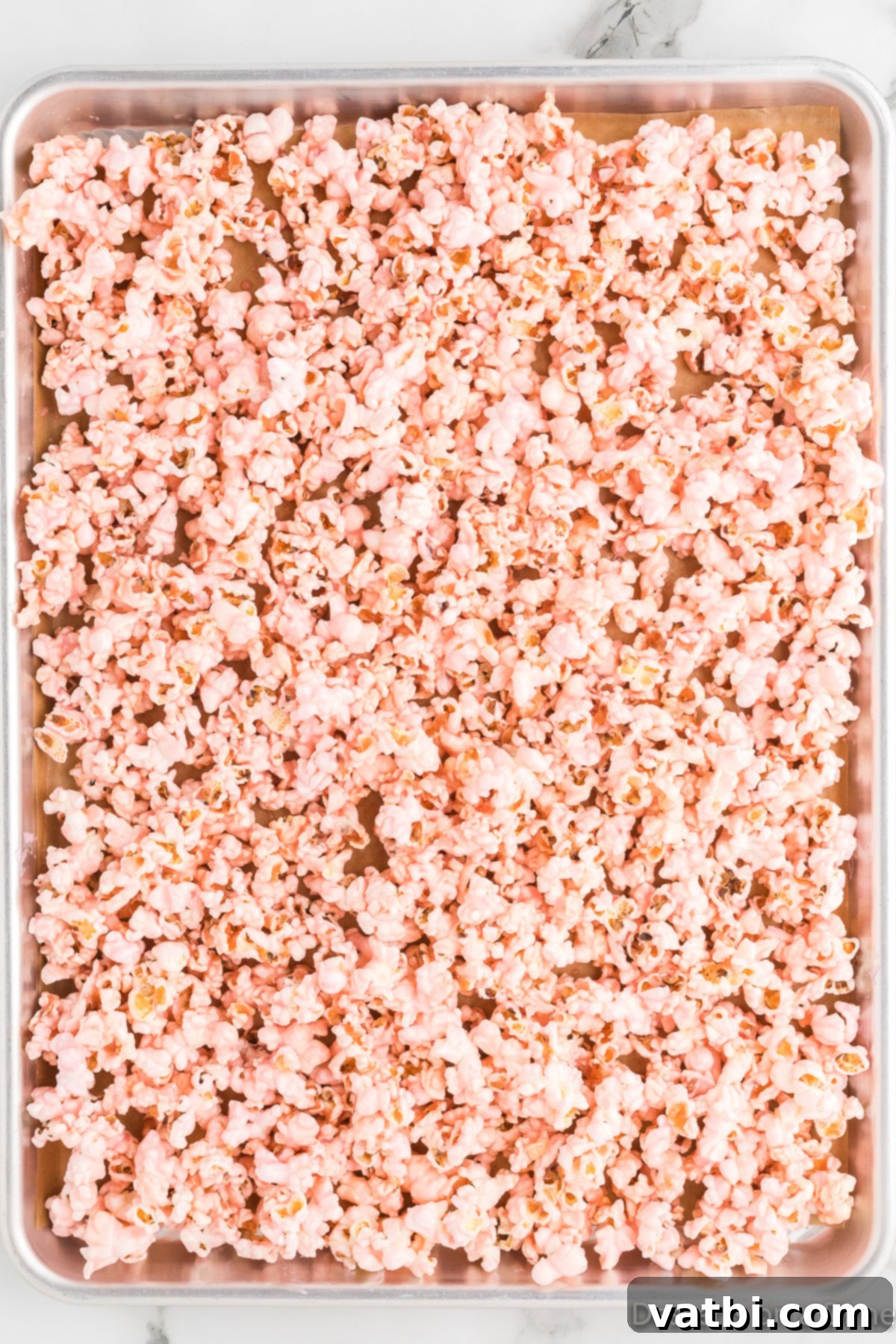 Blush Bites 7 Mixture spread on popcorn, being evenly coated.