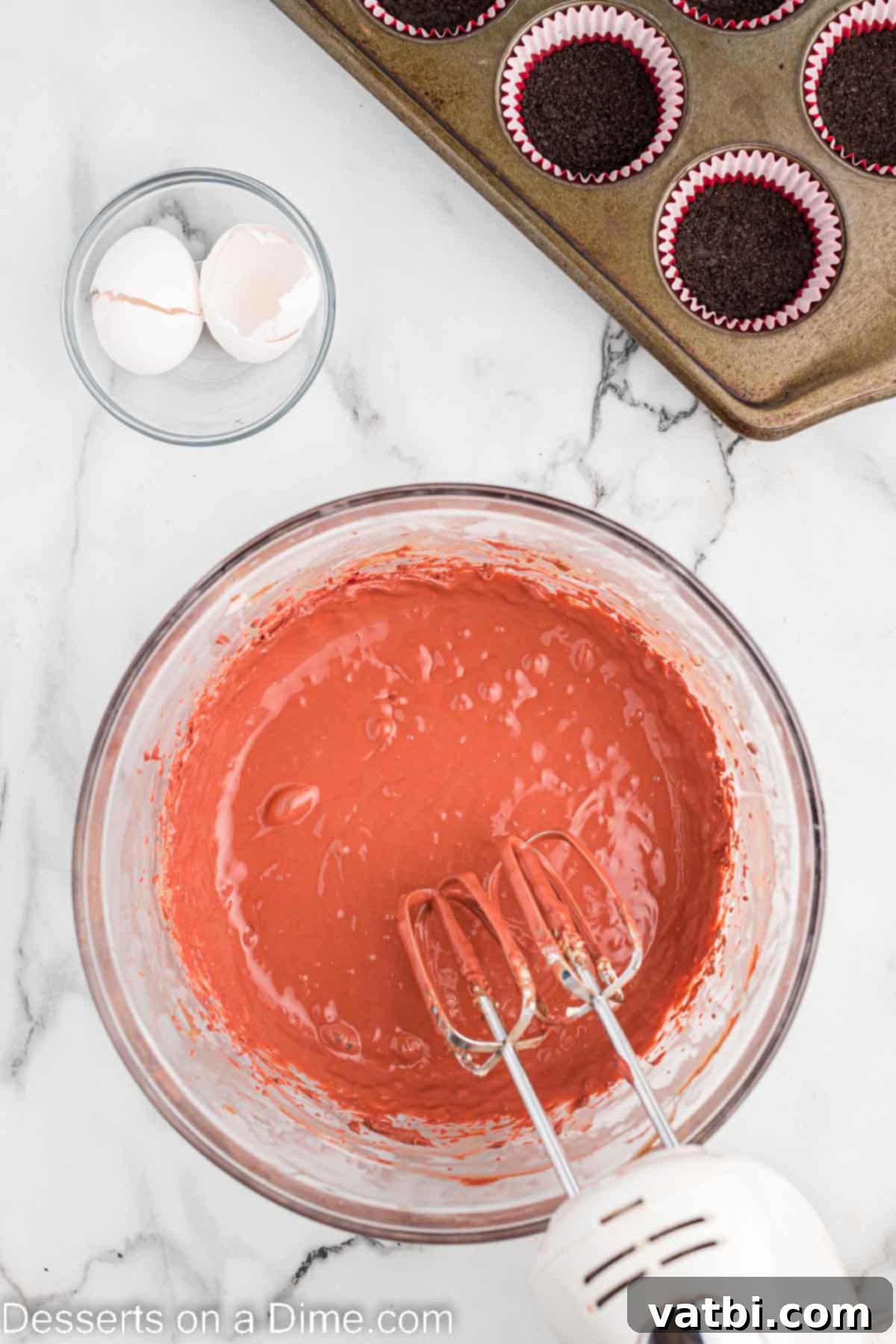 Cheesecake batter combined in a bowl, showcasing its smooth red color.