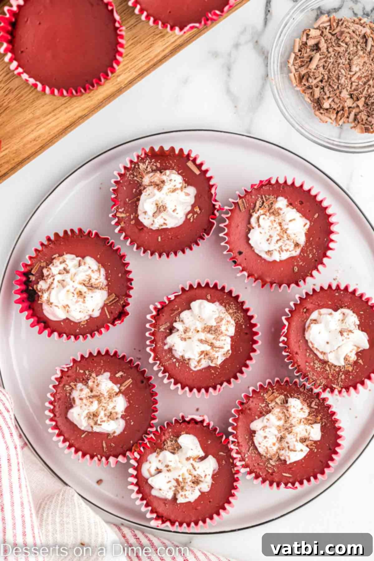 Mini red velvet cheesecake topped with cool whip and chocolate shavings, ready to be served.