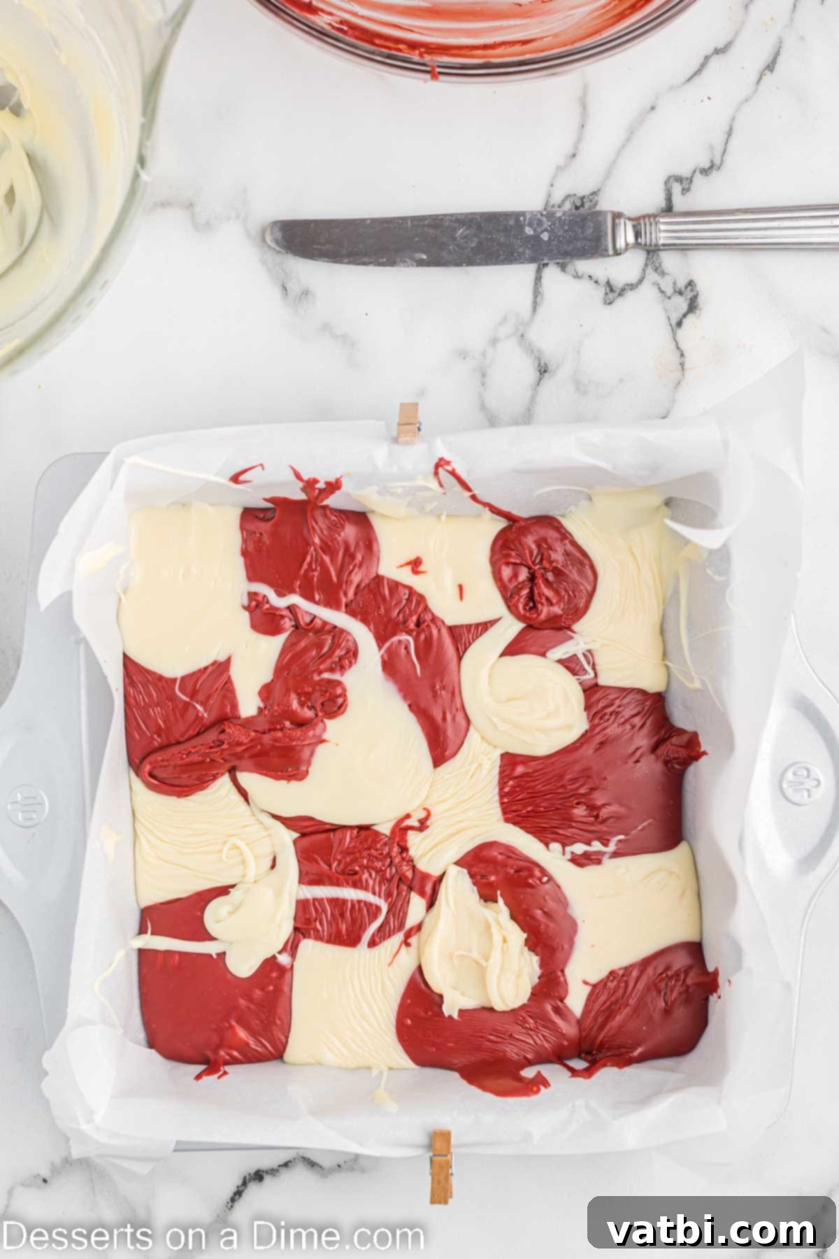 Decadent Red Velvet Fudge 7 Alternating spoonfuls of red and white fudge mixture spread into a baking dish, creating a patchwork effect.