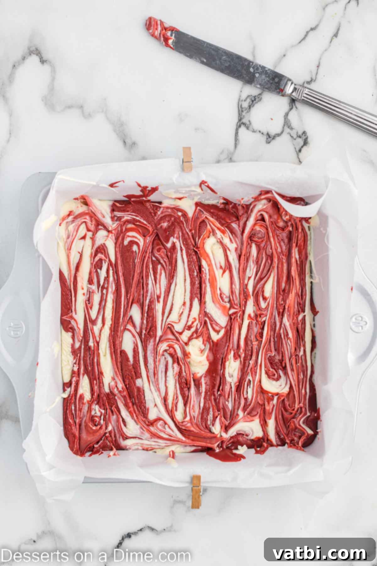 Decadent Red Velvet Fudge 8 Fudge mixture being swirled with a knife in a baking dish, creating beautiful marble patterns.