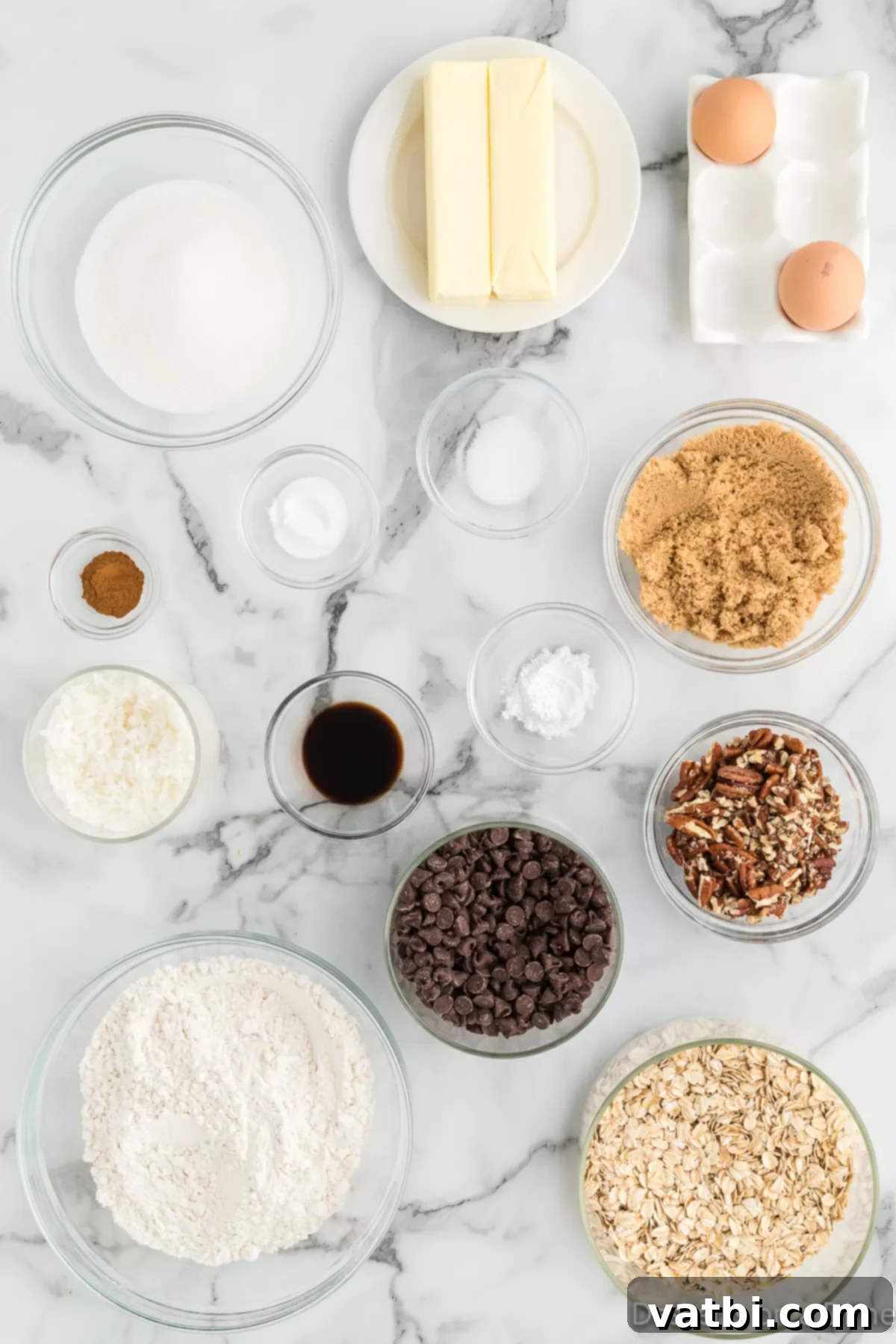 Loaded Cowboy Cookies 3 A flat lay of all the essential ingredients for making Cowboy cookies: flour, baking soda, softened butter, brown sugar, granulated sugar, eggs, vanilla extract, old-fashioned oats, chocolate chips, pecans, and coconut flakes.