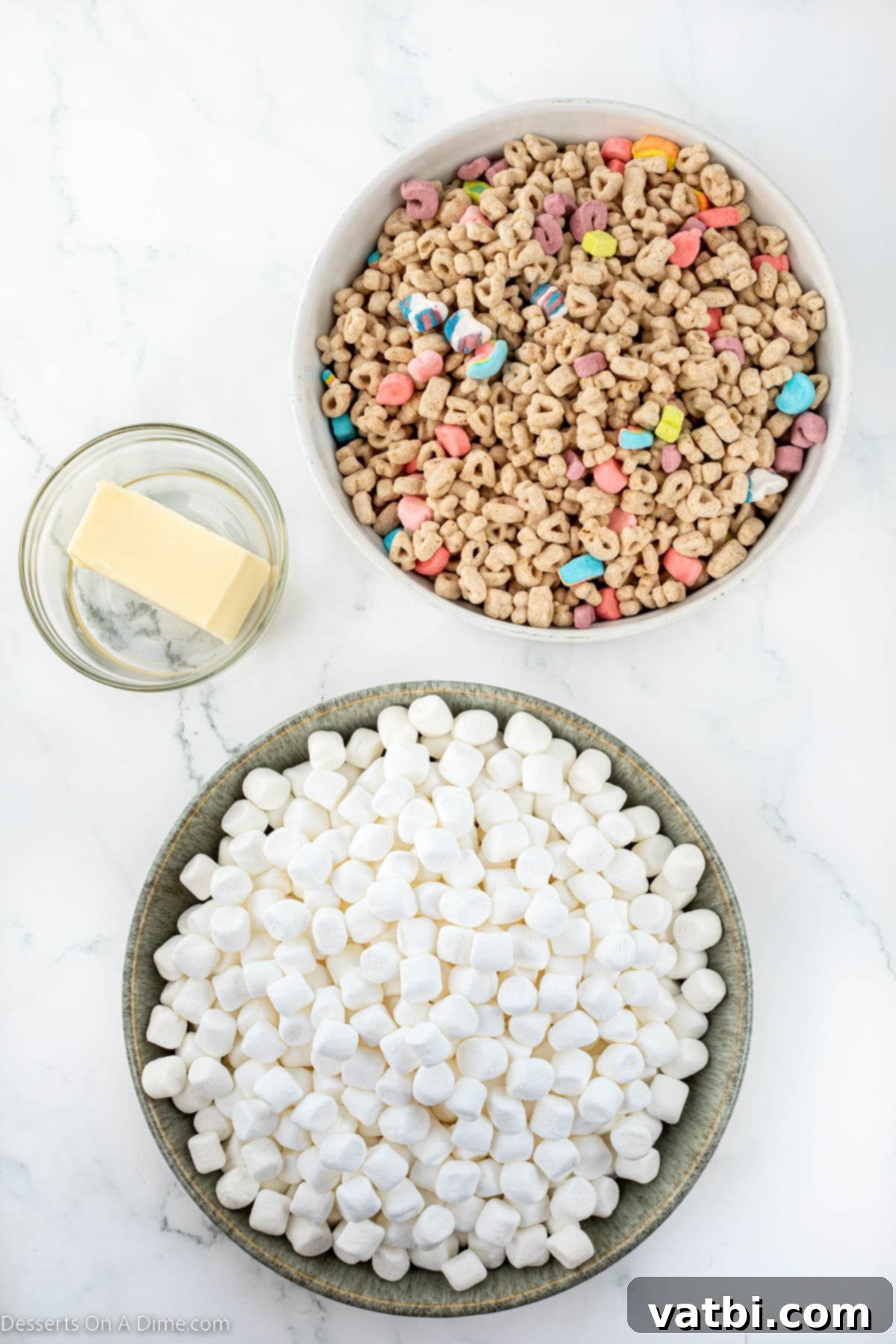 Lucky Charms Treats 3 Ingredients for Lucky Charm Treats - mini marshmallows, butter, and lucky charms cereal, laid out on a table.