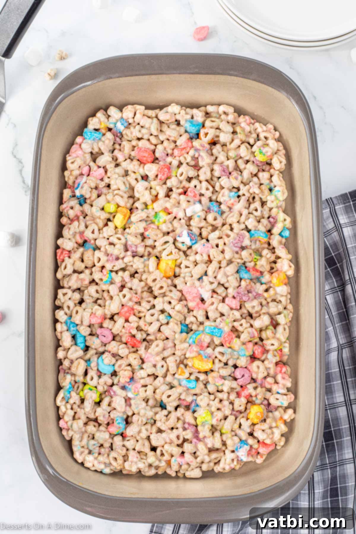 Lucky Charms Treats 6 Lucky Charms mixture being spread into a baking pan.