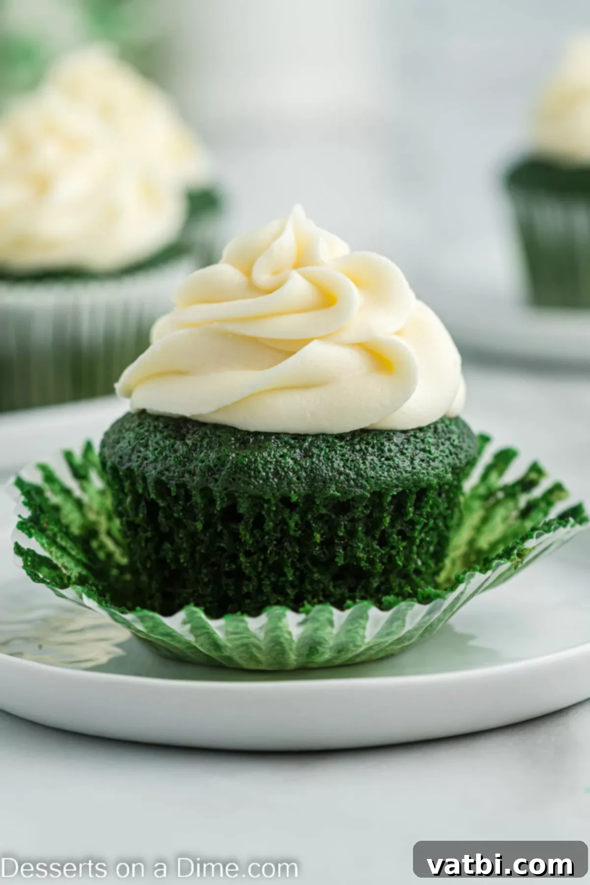 Lush Green Velvet Cupcakes 2 A vibrant green velvet cupcake topped with fluffy cream cheese frosting and a sprinkle of festive green decorations, sitting on a elegant white platter.