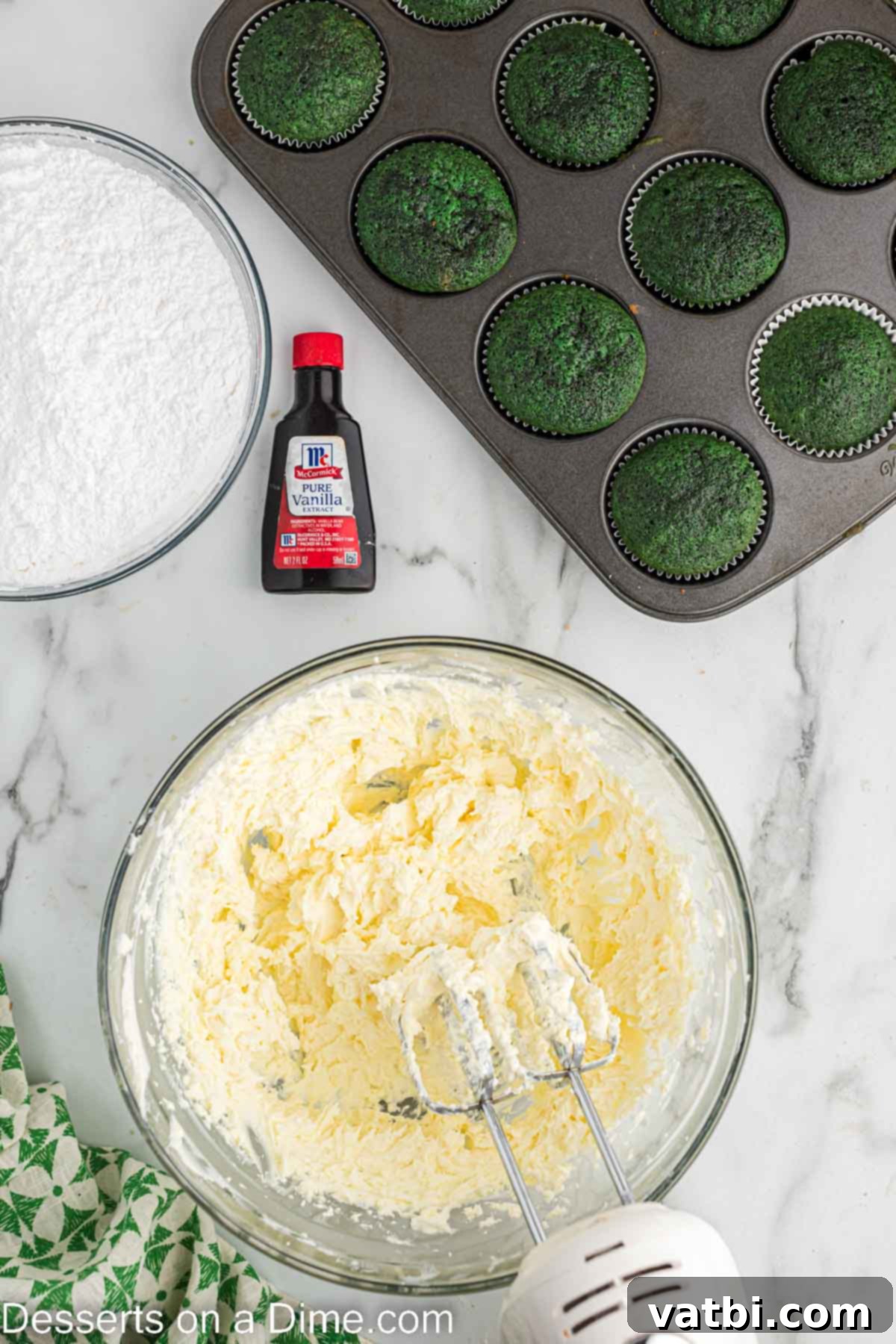 Lush Green Velvet Cupcakes 11 A bowl of cream cheese and butter being beaten together in a mixer until smooth and creamy for the frosting.