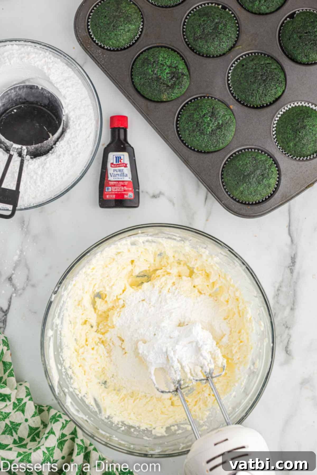 Lush Green Velvet Cupcakes 12 Powdered sugar being slowly added to the cream cheese and butter mixture in a mixing bowl, creating a smooth frosting.