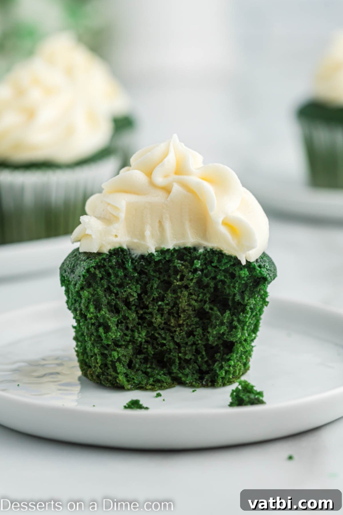 Lush Green Velvet Cupcakes 14 A single green velvet cupcake with cream cheese frosting, elegantly placed on a white plate, ready to be enjoyed.