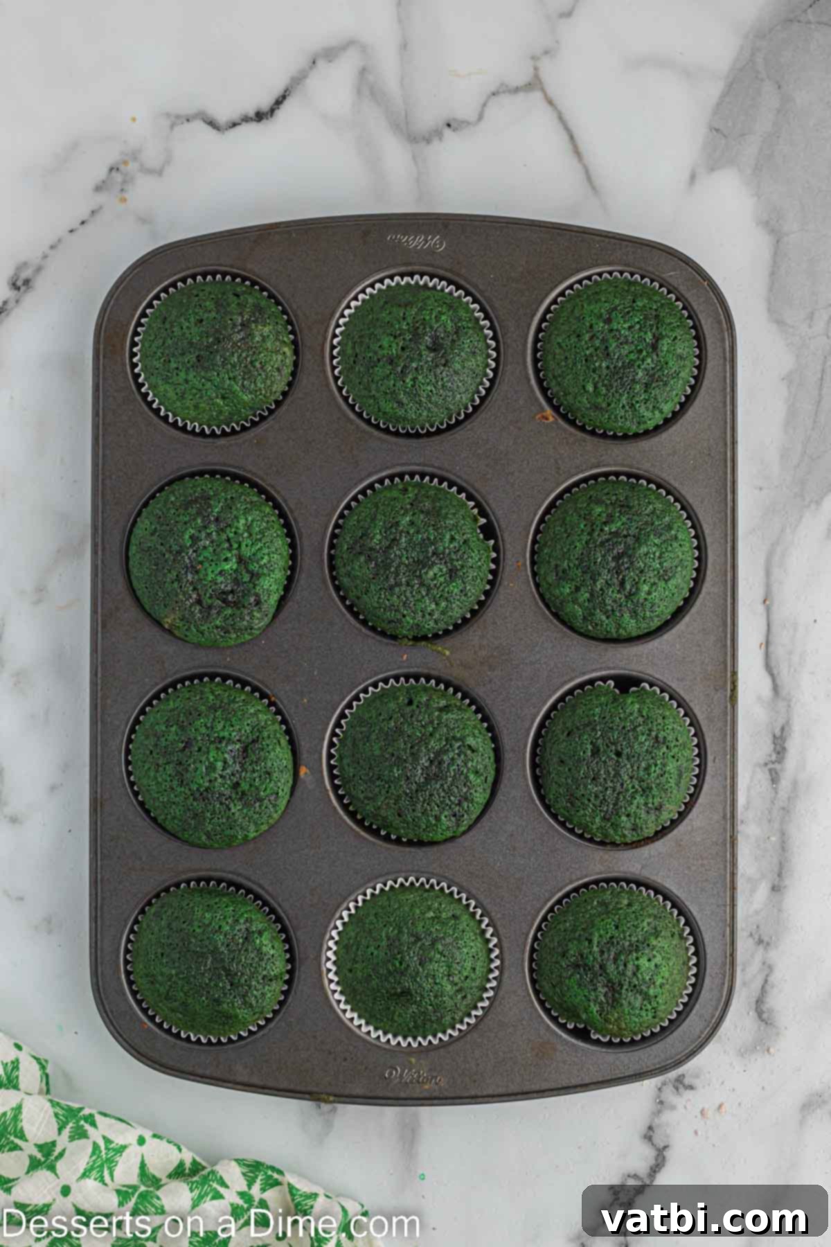 Lush Green Velvet Cupcakes 10 Baked green velvet cupcakes cooling on a wire rack after being removed from the oven.