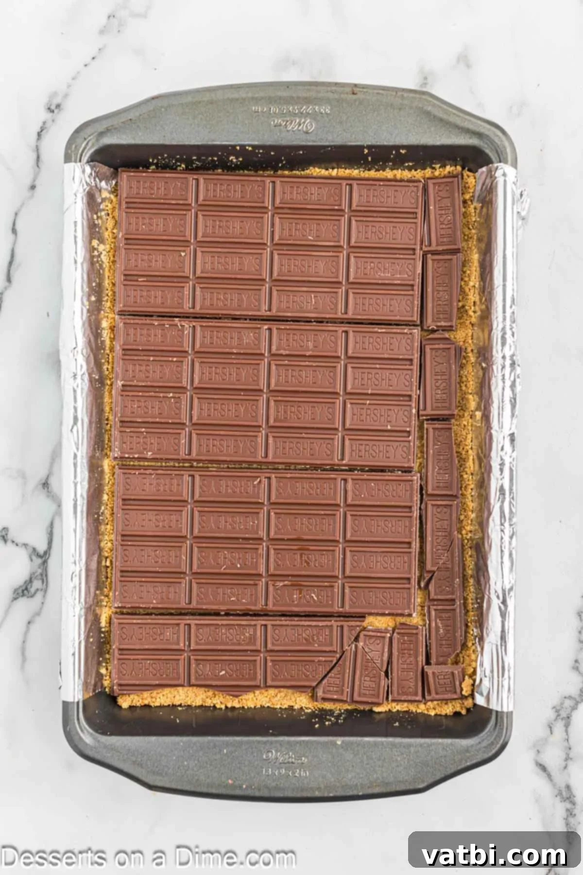 Gooey Smores Treat 6 Chocolate bars neatly placed on top of the baked graham cracker crust, ready to be melted.