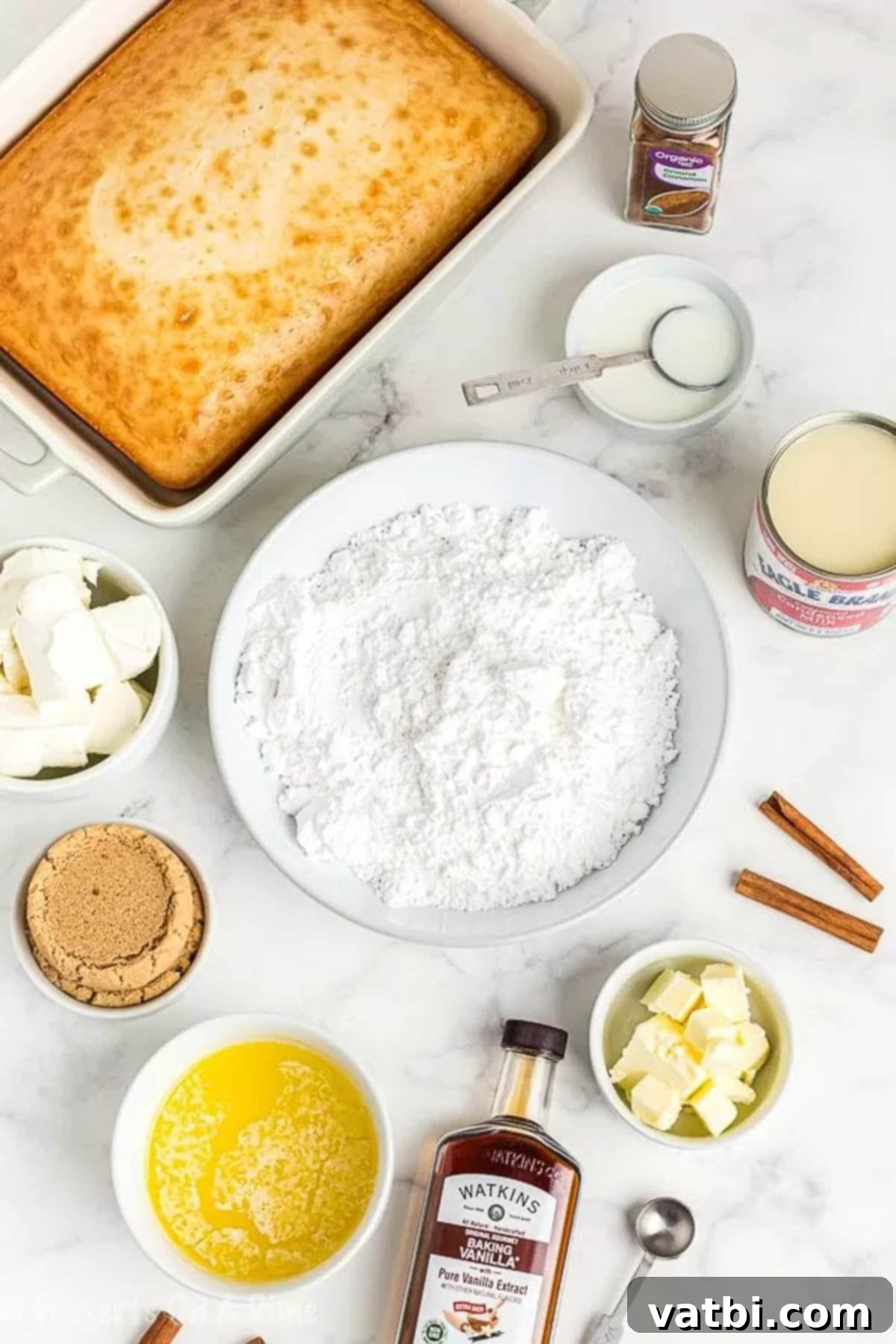 Cinnamon Roll Poke Cake Recipe is a yummy cake with lots of cinnamon and cream cheese icing. Enjoy everything you love about cinnamon rolls in an easy cake. A flat lay photograph displaying all the ingredients needed for Cinnamon Roll Poke Cake: white cake mix, butter, brown sugar, sweetened condensed milk, ground cinnamon, cream cheese, powdered sugar, milk, and vanilla extract.