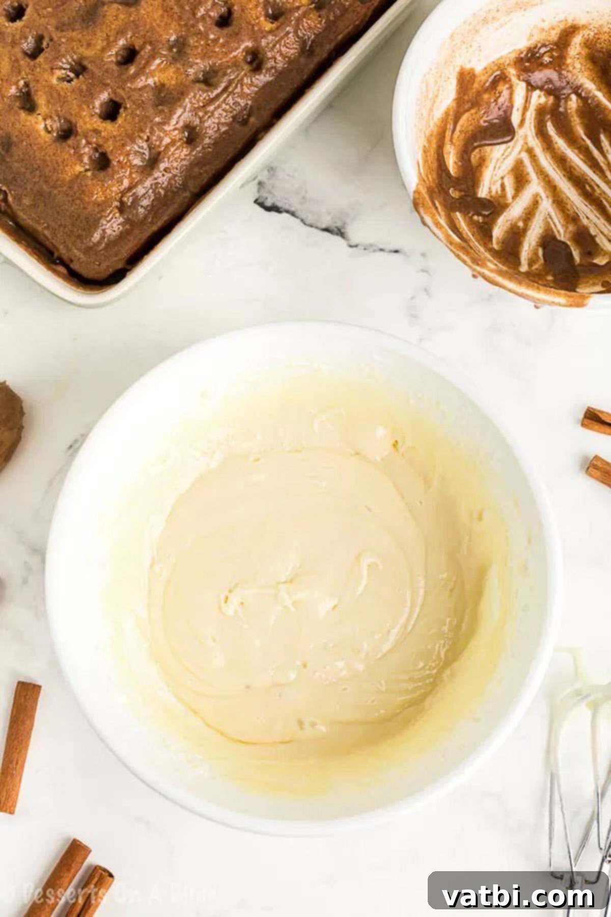 Irresistible Cinnamon Roll Poke Cake 7 A close-up of a mixing bowl showcasing creamy, perfectly combined homemade cream cheese frosting, ready to be spread.