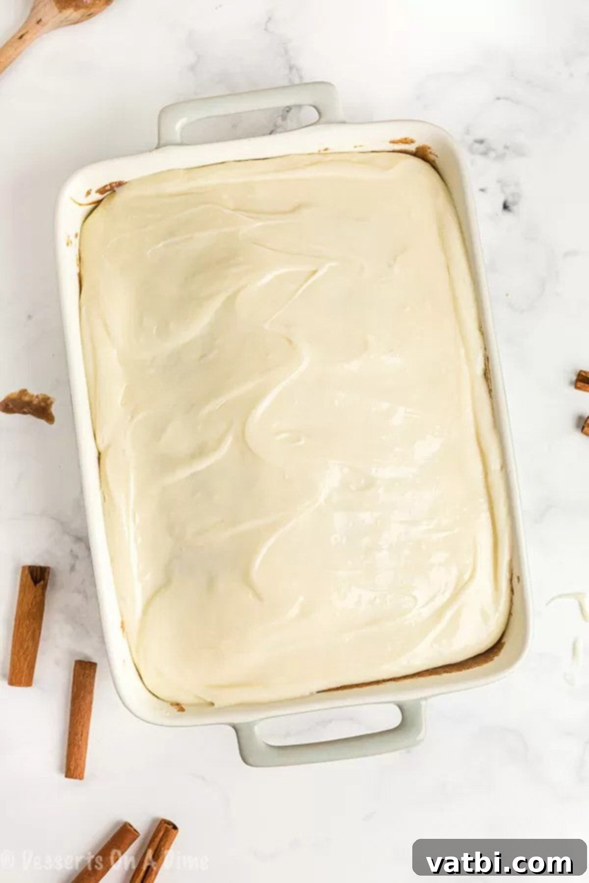 Irresistible Cinnamon Roll Poke Cake 8 Smooth, creamy cream cheese frosting beautifully spread over the cooled cinnamon roll poke cake, ready for serving.