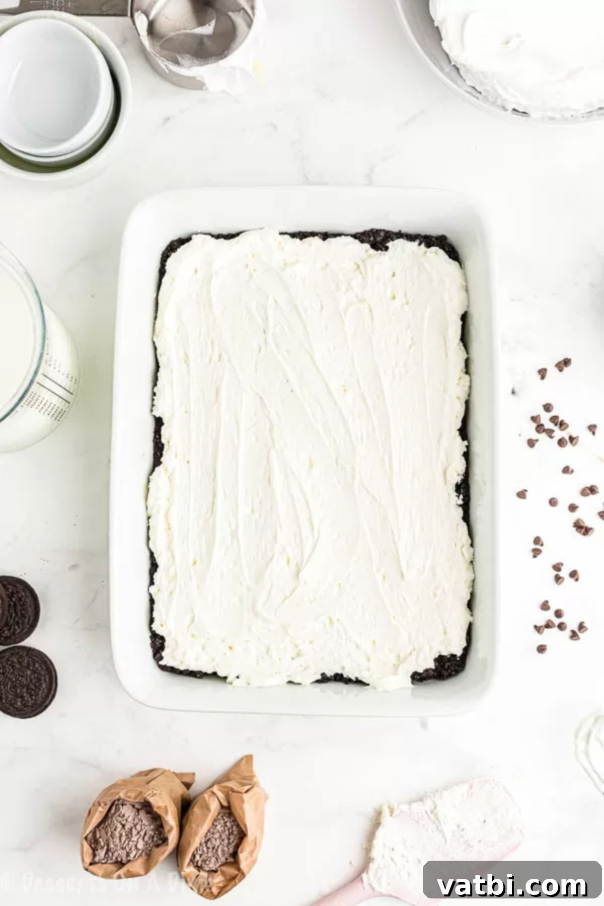 Decadent No-Bake Chocolate Lasagna 4 Whipped cream spread on top of dessert layers in a baking dish, ready for final toppings.