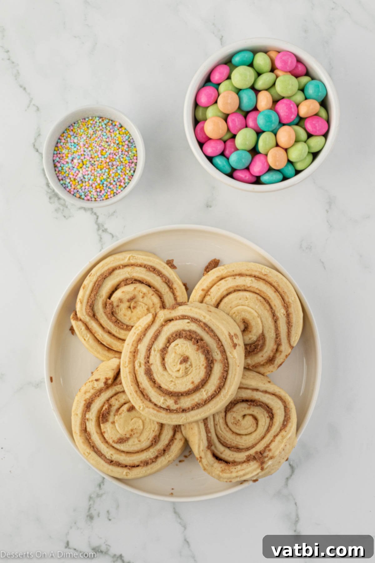 Hoppy Swirls 3 A visual display of the simple ingredients needed for Easter Bunny Cinnamon Rolls, including a can of Pillsbury Grands, colorful pastel sprinkles, and pastel M&Ms.