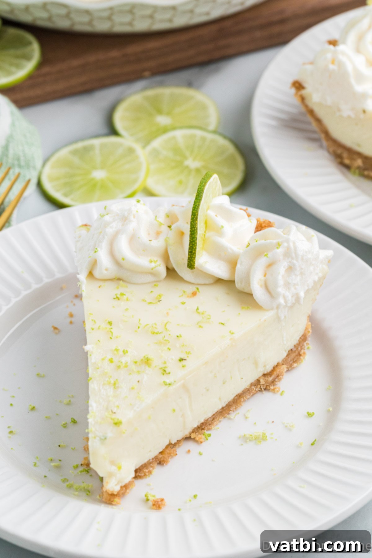 Simple Key Lime Pie Perfection 2 Slice of key lime pie on a plate, garnished with whipped cream and a lime slice.
