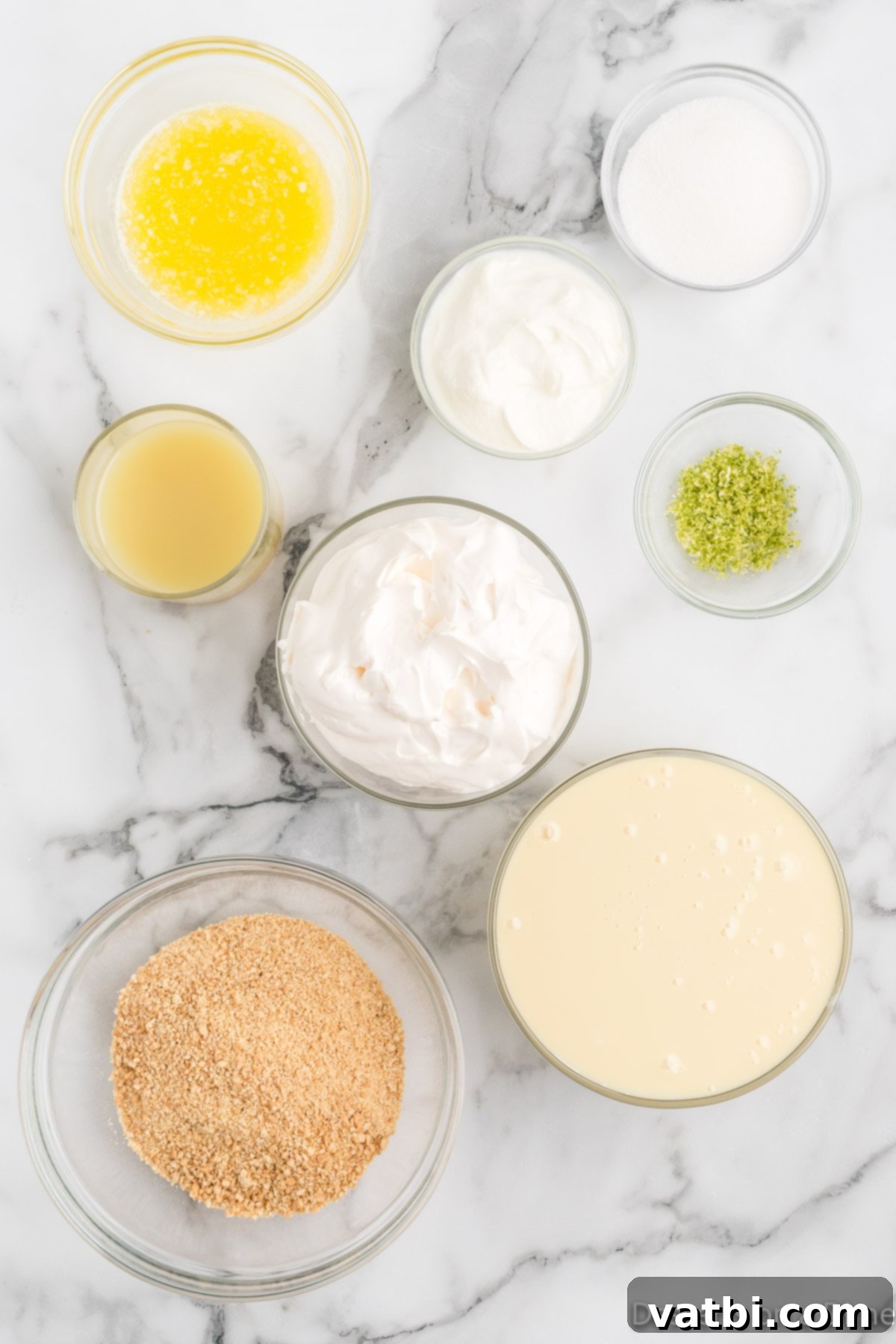 Simple Key Lime Pie Perfection 3 Ingredients for key lime pie laid out on a table - graham cracker crumbs, butter, sugar, sweetened condensed milk, sour cream, lime juice, and a bowl of whipped cream.