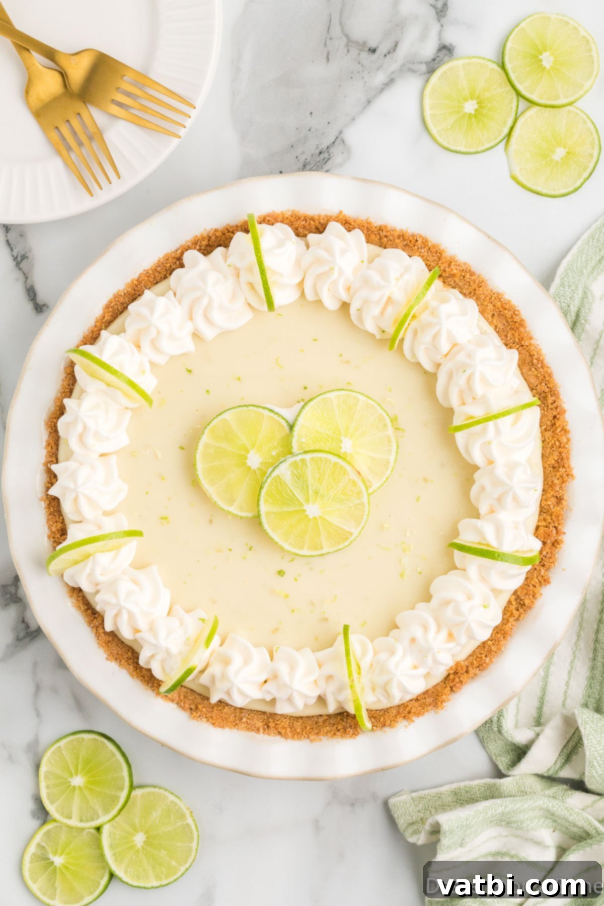 Simple Key Lime Pie Perfection 9 Baked and chilled key lime pie topped with whipped cream and lime slices.