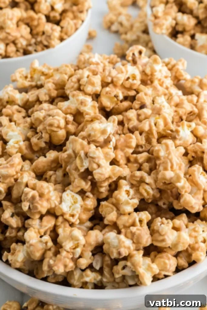 A large bowl filled with golden-brown Cookie Butter Popcorn, garnished with a drizzle of white chocolate, ready for serving. The popcorn pieces are evenly coated and appear delightful.