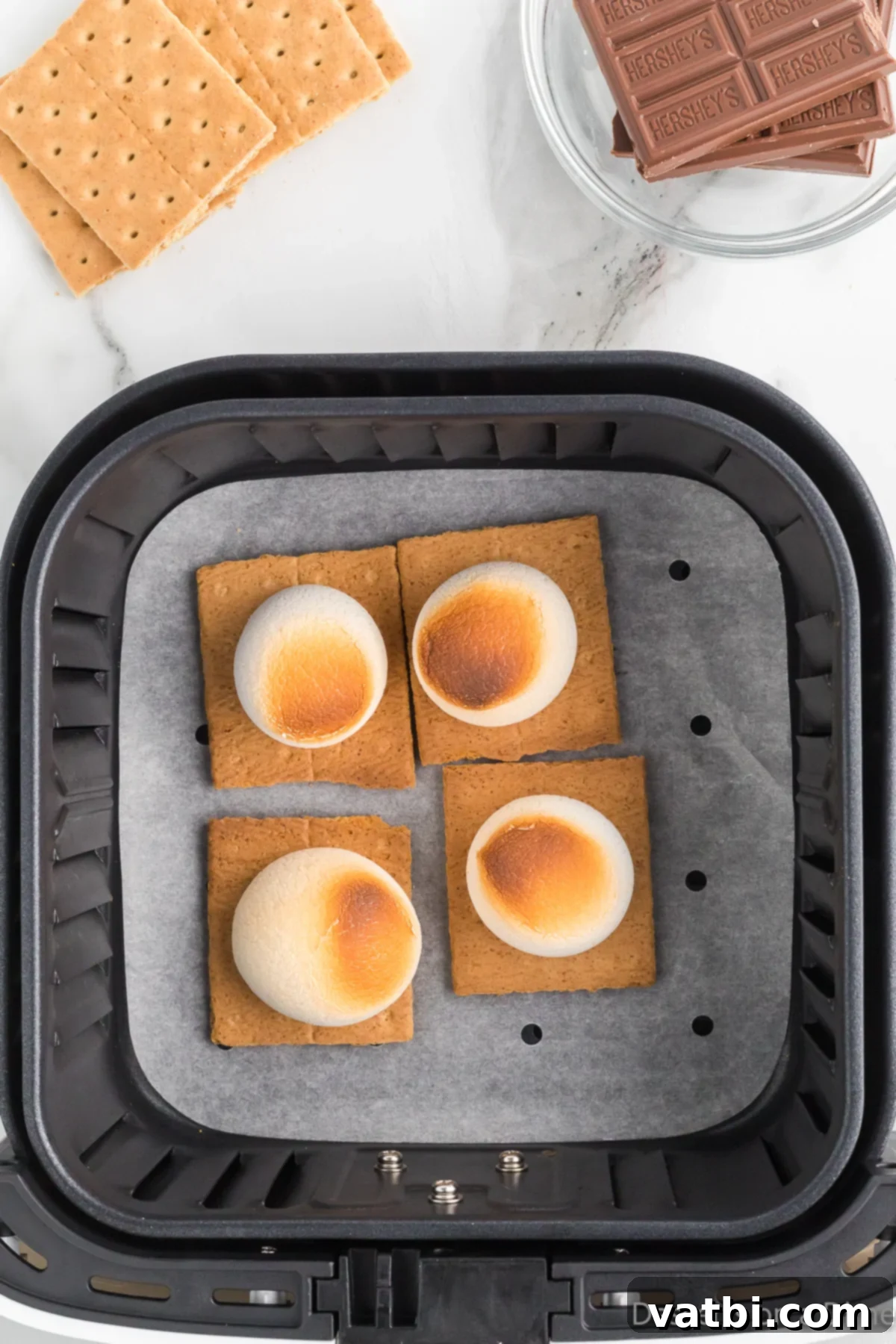 Toasted marshmallows, golden brown and slightly crispy, on graham crackers inside the air fryer.