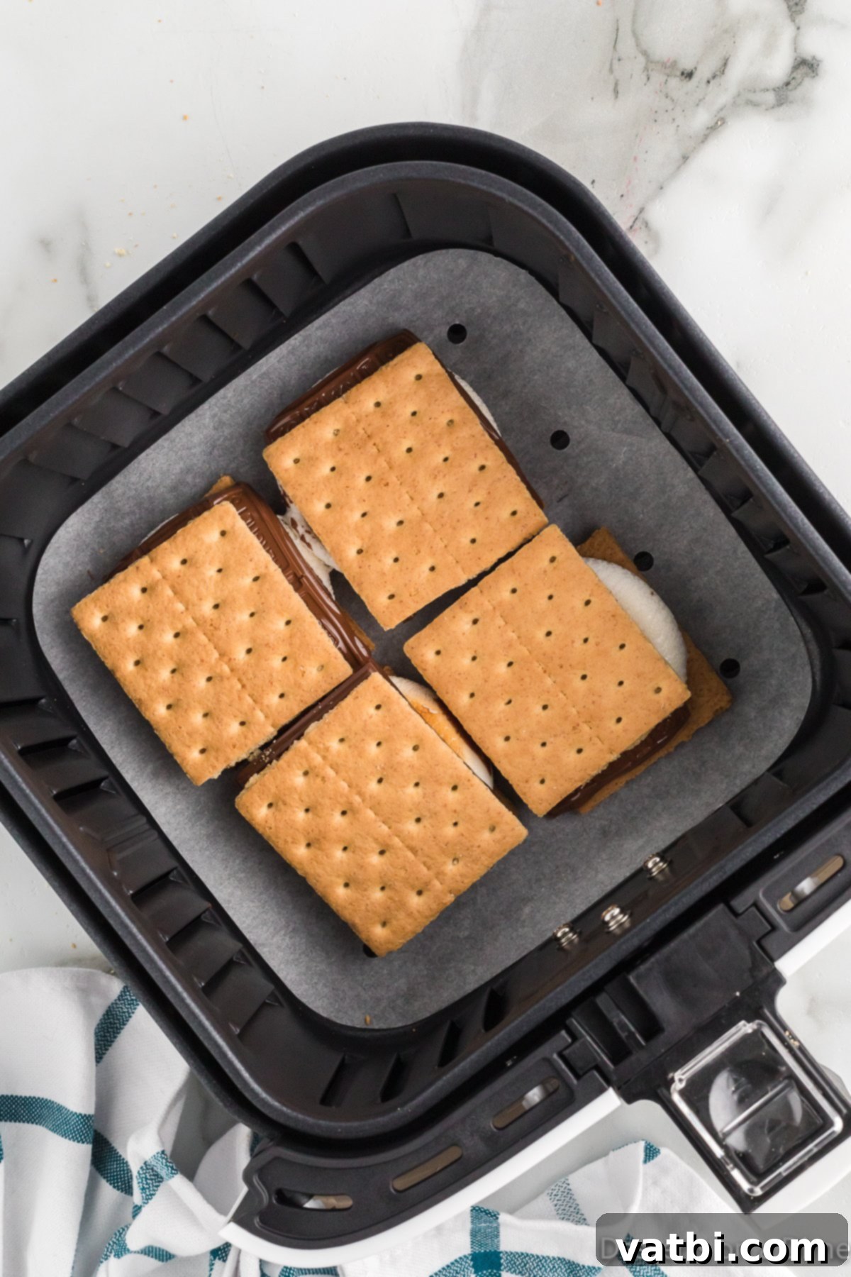 Chocolate bar pieces and the remaining graham cracker halves being placed on top of the toasted marshmallows.