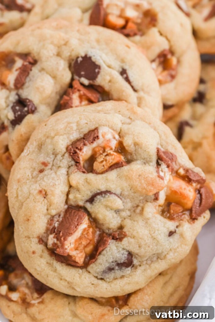 Freshly baked Snickers Cookies stacked together, showcasing their soft texture and melted candy pieces.
