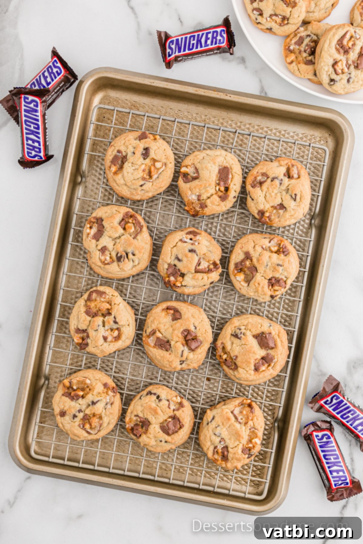 Warm Snickers cookies cooling on a wire rack.