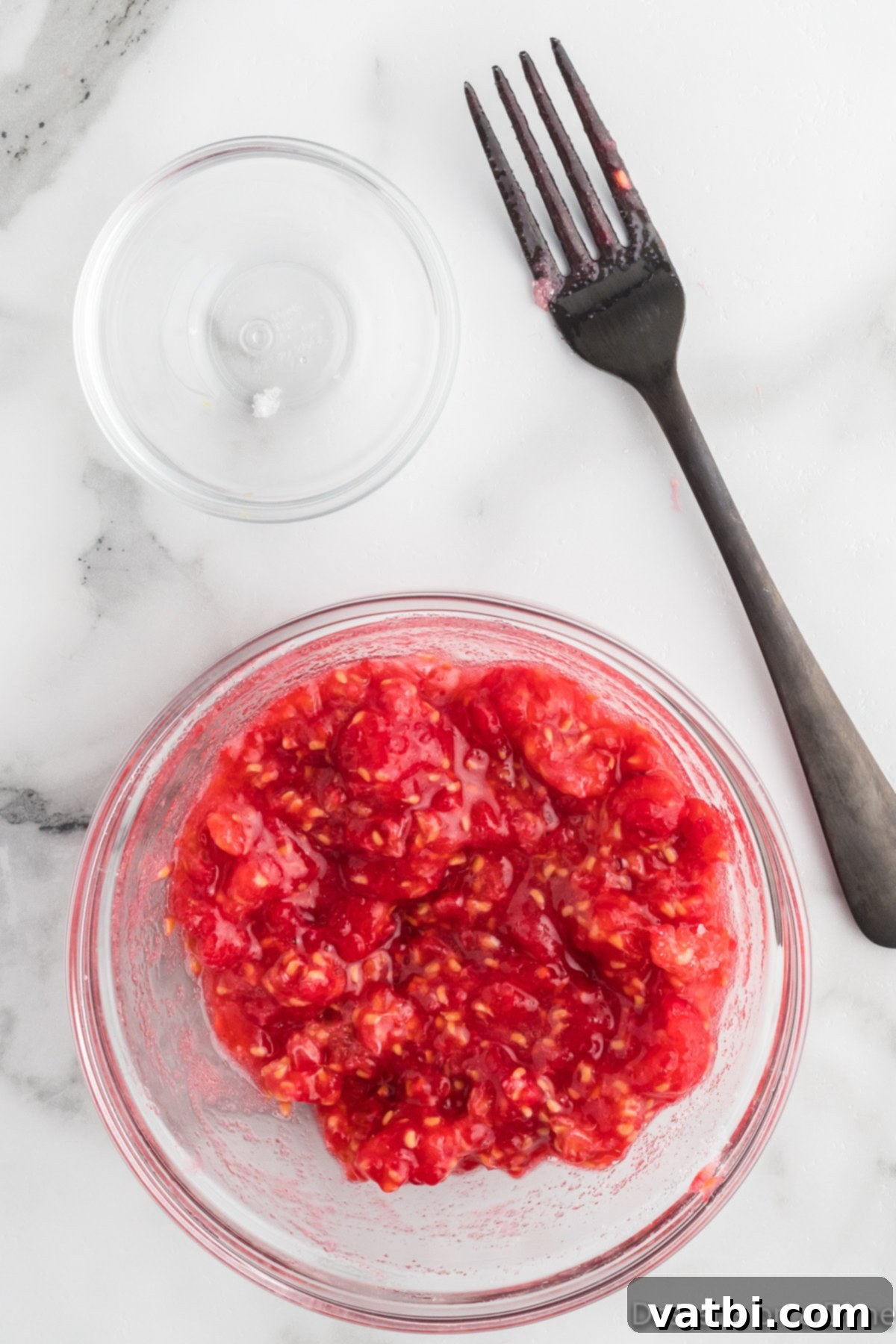 White Chocolate Raspberry Dream 5 Mashed raspberries in a bowl with their juices.