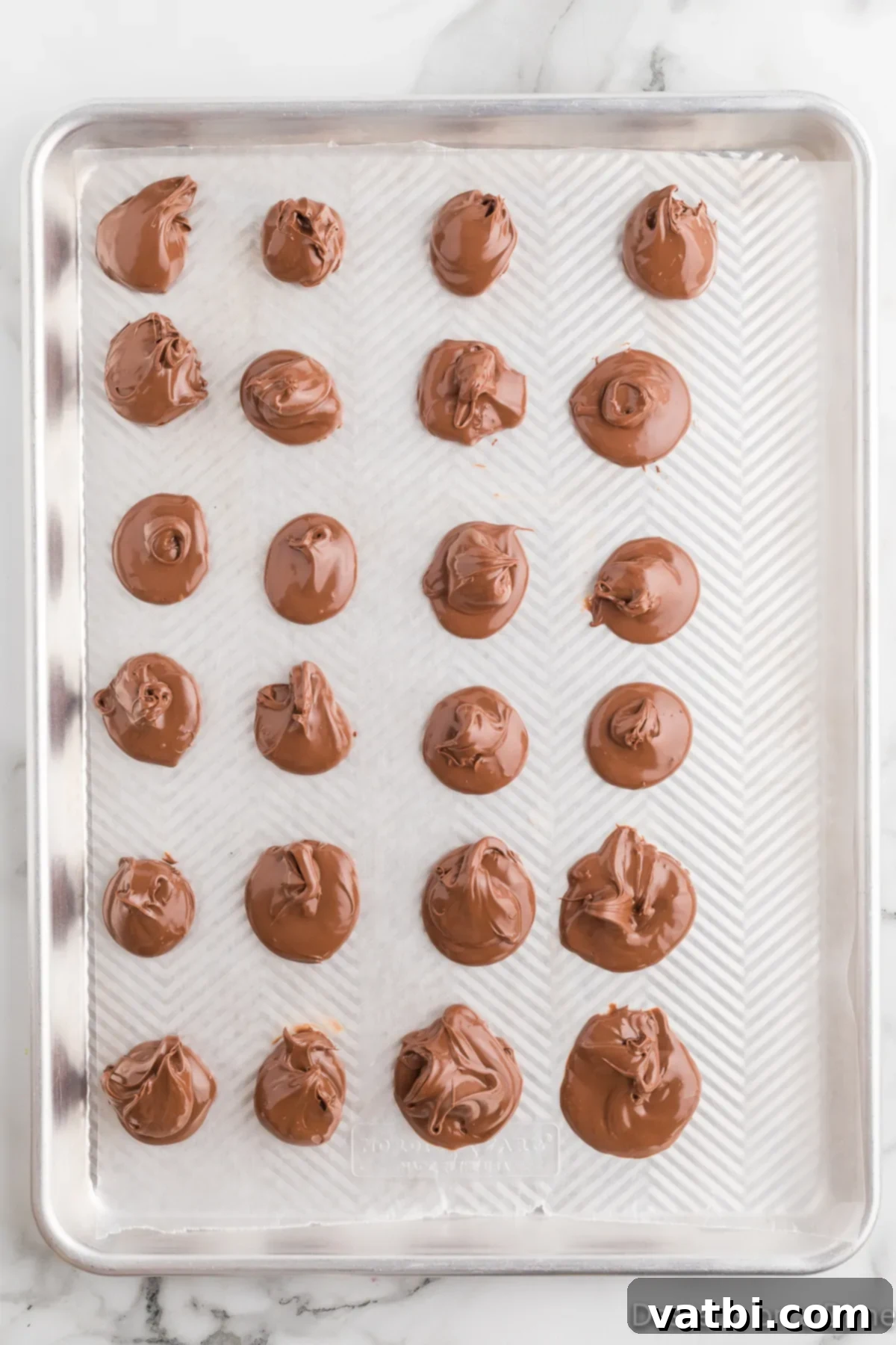 Decadent Nutella Stuffed Cookies 5 Small, round drops of Nutella portioned on a baking sheet lined with wax paper, ready to be frozen.