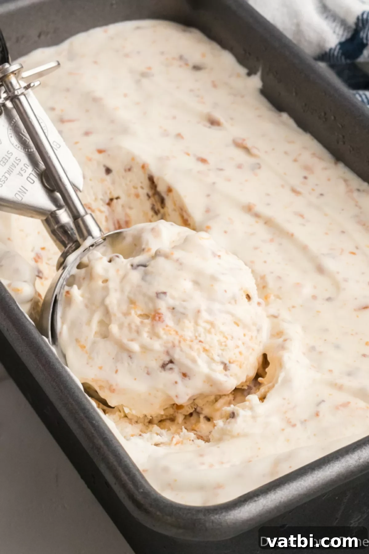 Crunchy Homemade Butterfinger Ice Cream 8 Ice cream in loaf pan being scooped.