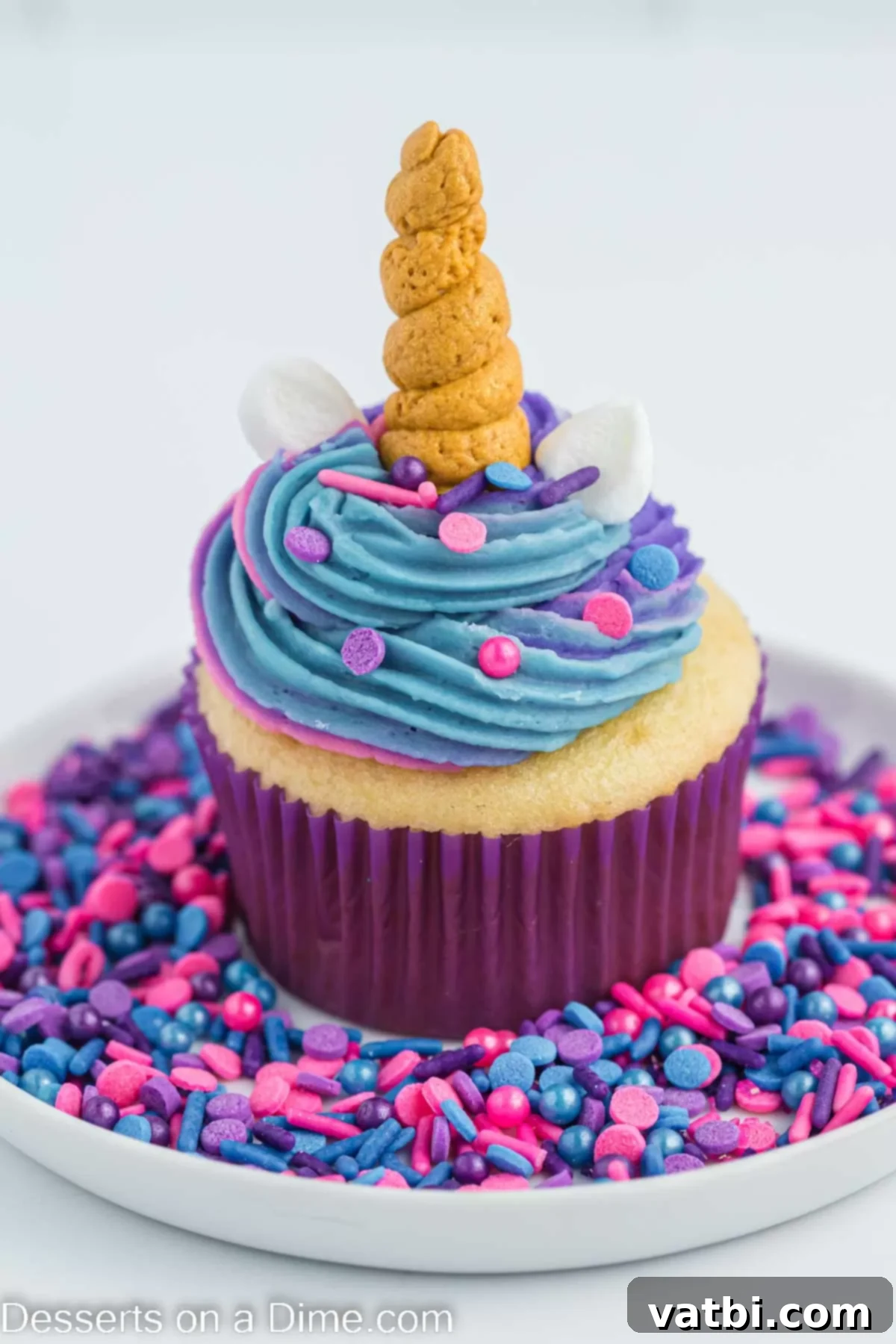 Magical Unicorn Cupcakes 11 A single unicorn cupcake on a white plate, adorned with sprinkles.