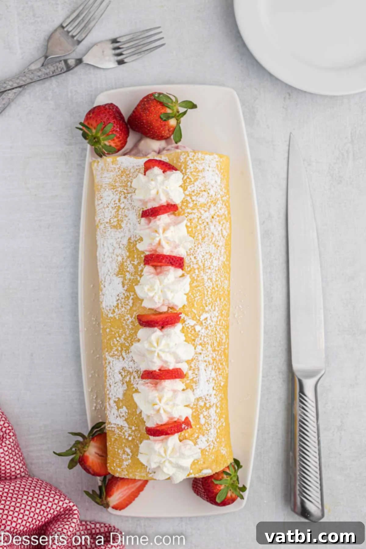 Strawberry Shortcake Swiss Roll 11 Cake rolled together and topped with fruit and powdered sugar.