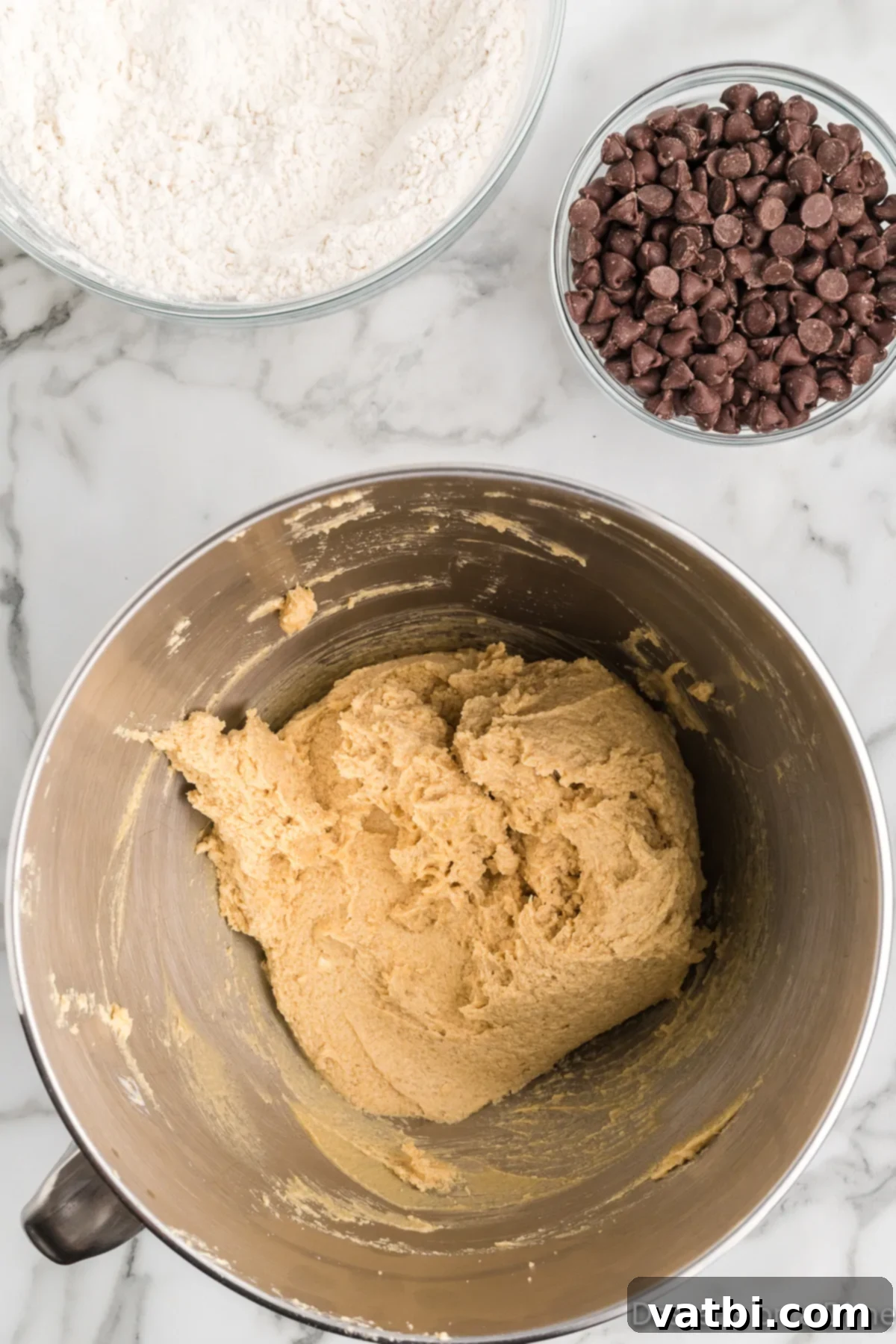 Mrs. Fields' Legendary Chocolate Chip Cookies 6 A close-up shot of wet and dry cookie ingredients being mixed together in a bowl, forming a dough.